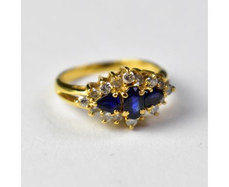 An 18ct gold diamond and sapphire ring, the central oval claw set sapphire flanked by two claw set pear-shaped sapphires, wit