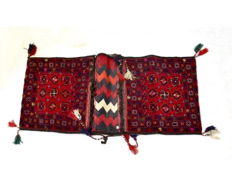 An Afghan Beshir hand knotted donkey bag with central panel of nine medallions within stepped geometric border, with tassels,