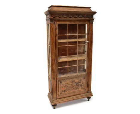 An early 20th century Continental oak display cabinet, the caddy top above ribbon applied frieze, with glazed upper section t