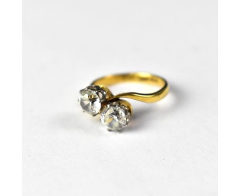 An 18ct gold two-stone dress ring, the two platinum claw set white stones in a crossover style (possibly white sapphire), siz