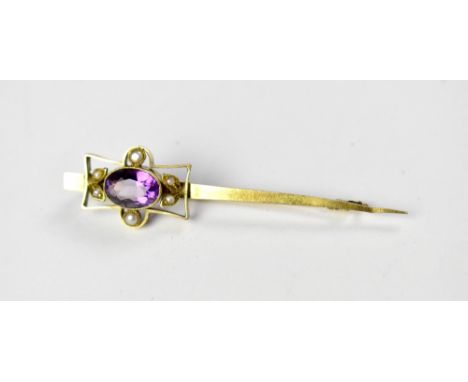An Edwardian 9ct gold bar brooch with an oval bezel set amethyst, with six small seed pearls on the shaped outer mount, on a 