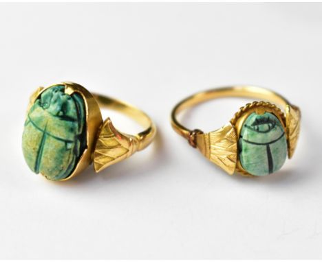 Two yellow metal Art Deco style Egyptian inspired yellow metal rings, both with scarabs of different sizes and fan shoulders,