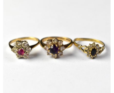 Three 9ct gold cluster rings comprising an example set with amethyst-coloured stone within a flower cluster of white stones, 