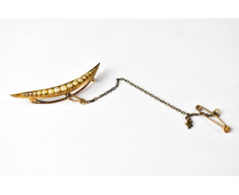An Edwardian-style long crescent brooch with graduated small seed pearls, on a yellow metal frame with safety chain, length 5