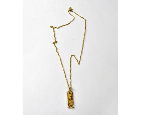 A yellow metal Egyptian pendant with central vertical line of hieroglyphics, Egyptian hallmarks, approx 4.6g, mounted on a ro