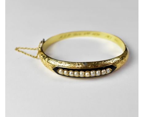 A late 19th century hinged bracelet with central line of ten inset seed pearls within a black enamelled border, raised above 