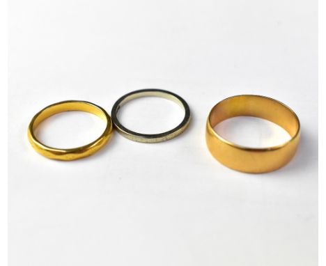 Three wedding bands comprising a 22ct gold wide ring, size S, approx 5g, an 18ct white gold ring, size M1/2 and an 18ct yello