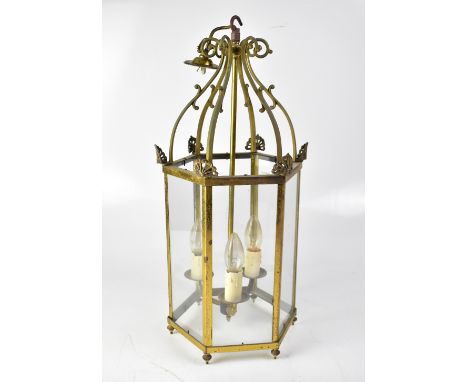 A hexagonal brass-effect lantern-style ceiling light with three candle-effect lights below a scrolling mount, height approx 5