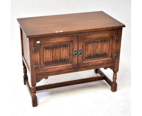 OLD CHARM FURNITURE; an oak hi-fi cabinet with hinged lid above pair of panelled doors with linen fold decoration, above bobb