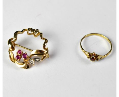 A 9ct gold open circular brooch with a small floral design of three claw set rubies and two small leaves set with two tiny di