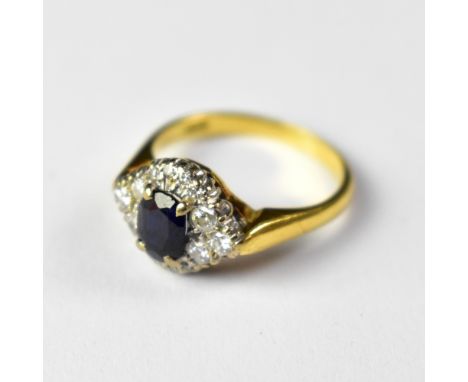 An 18ct gold sapphire and diamond ring, the claw set oval sapphire above a table comprising three small diamonds to each side