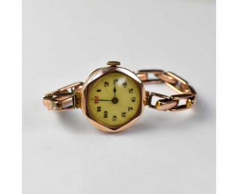 A ladies' vintage 9ct gold head wristwatch, the white dial set with Arabic numerals and red 12, crown wind movement, on a 9ct