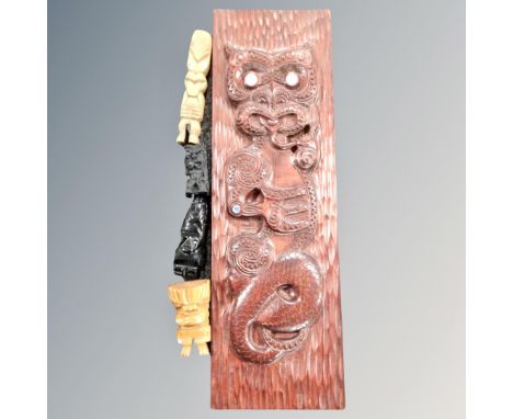A New Zealand carved wooden Tiki wall hanging with mother of pearl inlaid eyes, length 60 cm, together with a carved obsidian