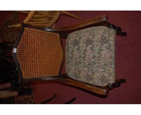 An early 20th century oak cane back open arm chair, having a floral tapestry upholstered stuff over seat, width 56cm