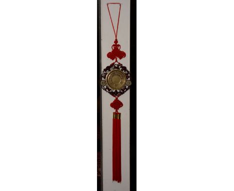 A Chinese brass, jade and hardwood lucky charm plaque with tassel, the circular brass insert decorated with moulded symbols a
