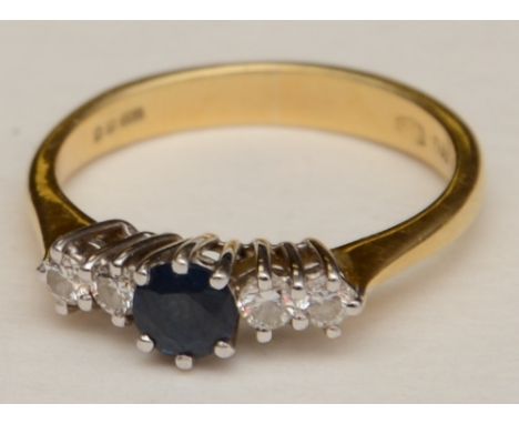 An 18ct gold sapphire and diamond five stone ring, the central round cut sapphire mounted by two brilliant cut diamonds to ei