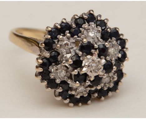 A 9ct gold sapphire and diamond flowerhead dress ring, the stepped formation featuring a central round cut diamond surrounded