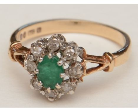 A 9ct gold emerald and diamond flowerhead ring, the central oval emerald surrounded by eight old cut diamonds, approx. 0.10ct