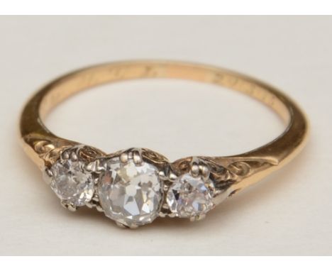 An Edwardian three stone diamond ring, with larger central cushion cut diamond flanked by two smaller round cut diamonds, app