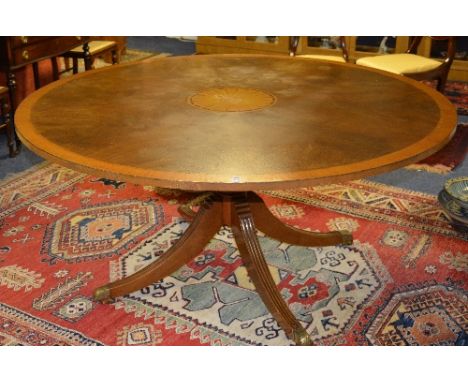 A large reproduction George III style circular dining table, raised on ring turned column and quad reeded supports with brass