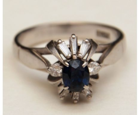 A platinum sapphire and diamond ring, the central oval cut sapphire surmounted by two brilliant cut diamonds and six baguette