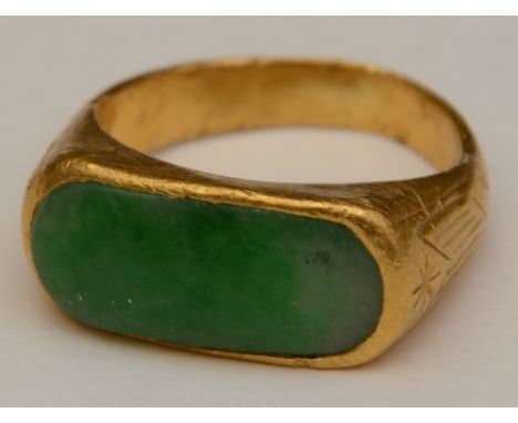 A 24ct gold and jade ring, with oblong green jade to the top with etched detail to both gold shoulders, stamped '9999 4' to u