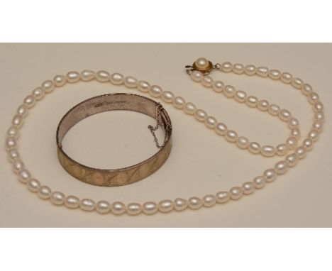 A string of white freshwater pearls, 29cm long (fastened), together with a silver bangle with hallmarks for Birmingham 1974 (