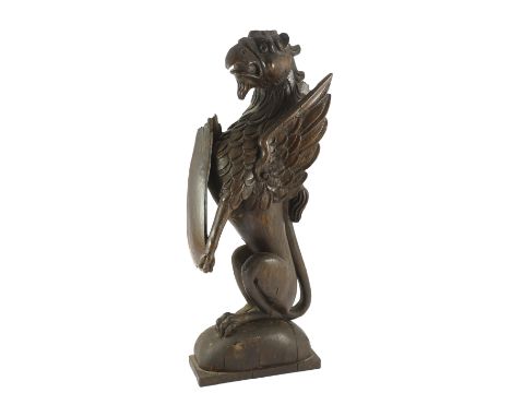 A 16th century Dutch carved oak model of a griffin rampant holding a shield, on domed base, 23cm wide, 9cm deep, 60cm high***