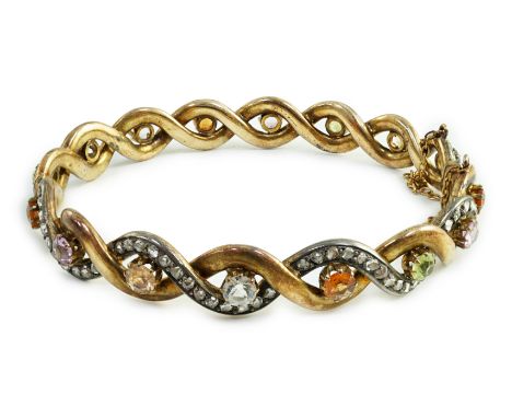A late 19th/early 20th century French 18ct gold and silver rose cut diamond and multi gem set spiral hinged bangle, maker's m