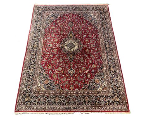 A Kashan burgundy ground carpet, the lobed central floral medallion within a dense floral field and wide conforming border, 4