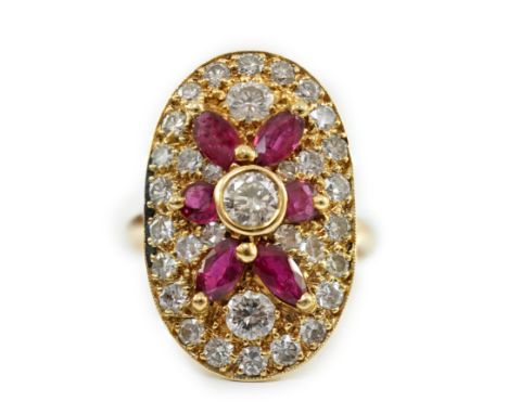 A modern gold, ruby and diamond set oval cluster ring, the central diamond bordered by brilliants and oval and round cut rubi