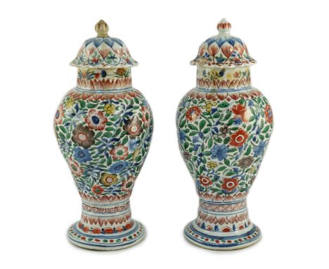 A pair of Chinese wucai spiral lobed baluster vases and covers, Kangxi, c.1680, each painted with lines of flowers, leaves an