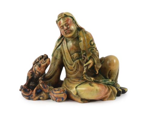 A Chinese soapstone group of a seated luohan and lion-dog, 19th/20th century, the ascetic holding a leaf in his left hand, re