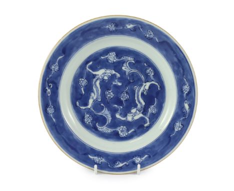 A Chinese blue and white ‘dragon’ plate, Kangxi period, painted with confronting dragons amid scrolling clouds on a blue grou
