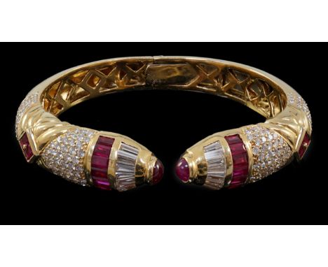 A modern 18ct gold, ruby and diamond cluster openwork hinged bangle, with serpent head style terminals and set with square, b