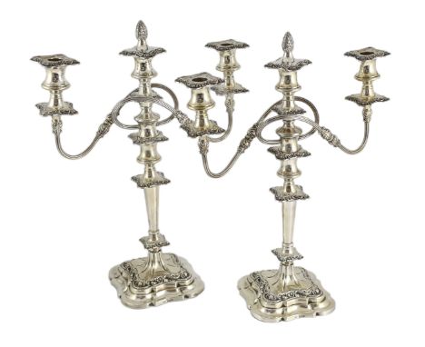 A pair of George VI silver two branch three light candelabra by George Howson, with reeded branches and tapering stems, on fo