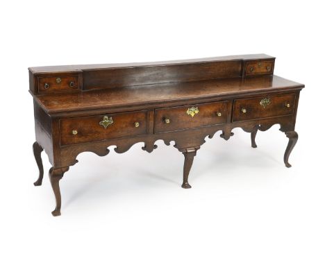 A late 18th century oak dresser base, the raised box back with a drawer to each end over three long drawers and scrolling apr