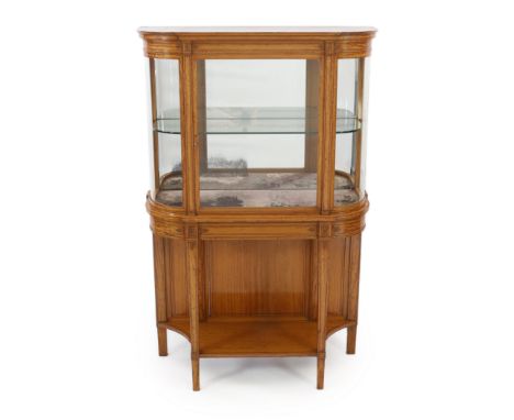 An Edwardian inlaid satinwood display cabinet of D shaped form with central glazed door over an understage, on squared tapere