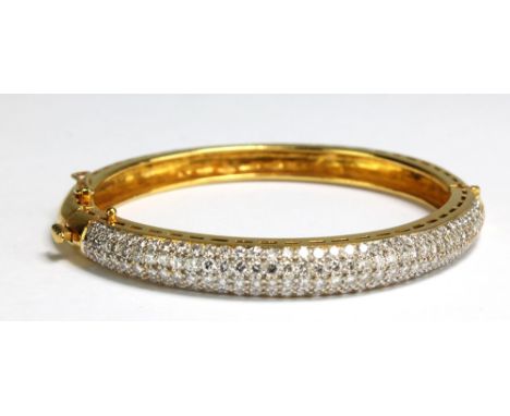 An Indian yellow metal pavé set hinged bangle, the upper platform set with one hundred and forty eight diamonds totalling app