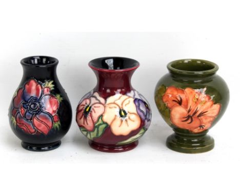 MOORCROFT; three small 'Hibiscus', 'Anemone' (second quality) and 'Pansy' pattern tubeline decorated vases on green, navy and