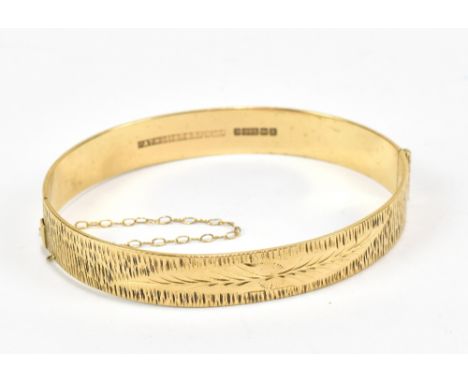 A 9ct yellow gold snap bangle with engraved detail, width approx 6.5cm, and approx 18.4g.