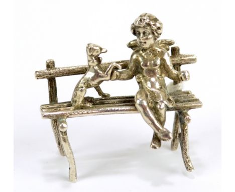 GEORGE BEDINGHAM; an Edward VII silver model of Cupid sitting on a bench with a dog, London import mark and letter for 1906, 