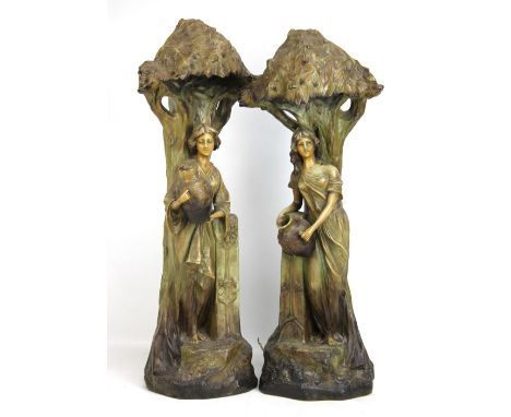 A pair of Goldscheider style painted terracotta Art Nouveau figures of female water carriers beneath branches, height 74cm.