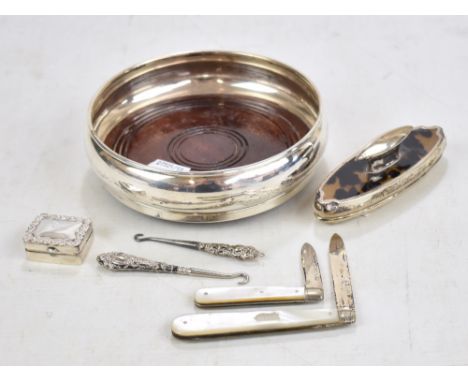 Two mother of pearl bodied silver bladed pocket fruit knives, a silver bottle coaster with wooden base, a nail buffer, miniat
