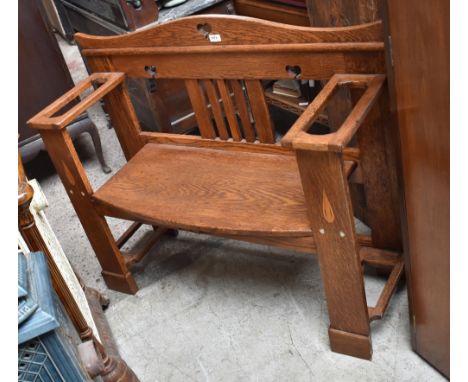 An Arts and Crafts oak and inlaid hall bench, the shaped raised back above twin arms set with lift-out pads originally for st