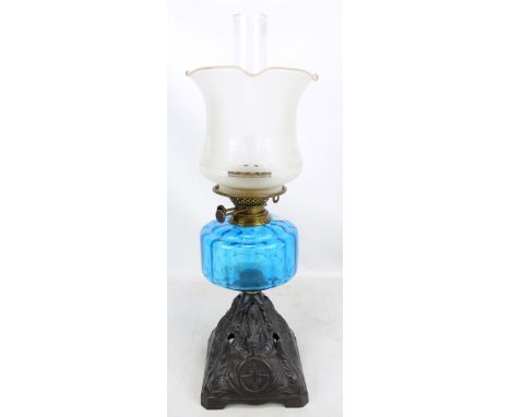 A cast iron lamp with etched shaped shade, turquoise coloured glass reservoir and pierced stepped base, height including chim