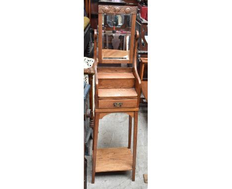 An Arts and Crafts oak dressing table of small proportions, the rectangular mirror with panel of embossed copper detail above