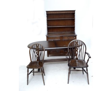 A reproduction oak dining room suite comprising oval dining table, dresser with boarded plate rack and eight associated chair