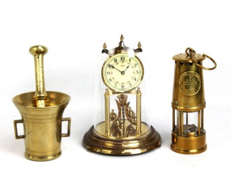 Three items to include an Eccles brass miner's lamp, a brass pestle and mortar and a modern Kundo mantel clock (3).