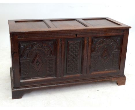 An 18th century and later oak coffer with triple panelled hinged lid above carved front raised on bracket feet, width 134cm.